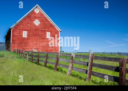 USA, Oregon, Joseph. Rote Scheune und Zaun in der Nähe der Wallowa Mountains in Oregon. Stockfoto