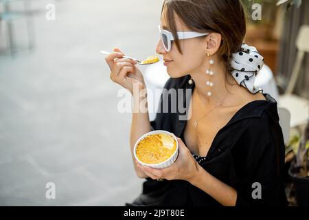 Frau, die im Restaurant im Freien Dessert mit Creme Brulee isst Stockfoto