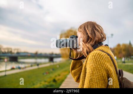 Profilfoto der ziemlich positiven Dame macht Fotos von Stadt Rever mit professioneller Kamera im Frühjahr Zeit. Schöne Fotografin fotografiert Stadt Stockfoto