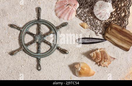 Kapitänsrad mit Fischernetz und Meeresmuscheln nautischen Thema Hintergrund Stockfoto