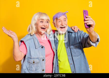 Foto von schönen Freund Freundin Rentner gekleidet Denim Outfit comminating moderne Gadget isoliert gelbe Farbe Hintergrund Stockfoto