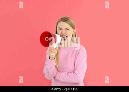 Junge Frau mit Megaphon auf rosa Hintergrund Stockfoto