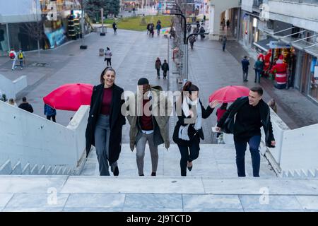 Eine Gruppe von multirassischen Geschäftsleuten geht die Sterne hoch und redet lächelnd Stockfoto