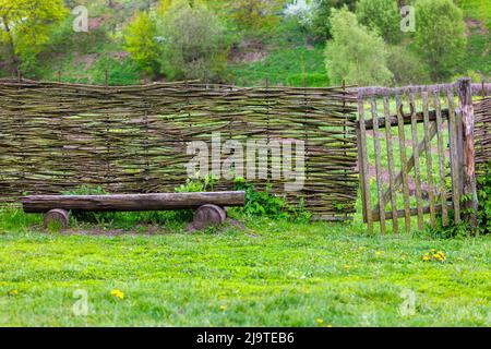 Horizontaler Wasserzaun mit Wicket und Holzbank in der Nähe Stockfoto