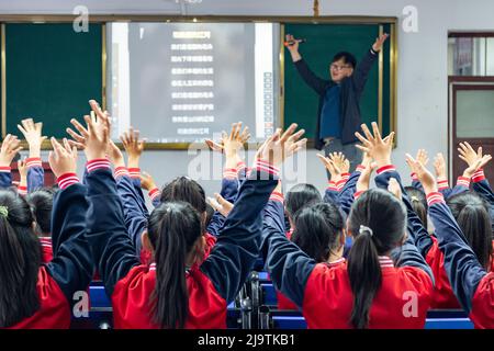 (220525) -- HARBIN, 25. Mai 2022 (Xinhua) -- Lehrer Zhang Yu unterrichtet Kinder im Musikunterricht an der zentralen Grundschule der Stadt Renmin in Anda, nordöstlich der Provinz Heilongjiang, 24. Mai 2022. Die Musikklasse der Grundschule wurde im April 2019 gegründet. Die Lehrer der Klasse passen die Texte der populären Lieder an, damit die Kinder singen können, und unterrichten sie ihnen dann während der Mittagspause oder der Clubaktivität. Die Kinder-Chorus-Videos wurden auf kurzen Videoplattform veröffentlicht, die von vielen Netzzenen beliebt waren und über 1 Millionen Fans verdienten. Mit den Inkreas Stockfoto