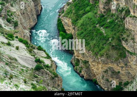 Blick von oben auf einen schnellen Gebirgsfluss, der am Fuße eines tiefen Canyons fließt Stockfoto