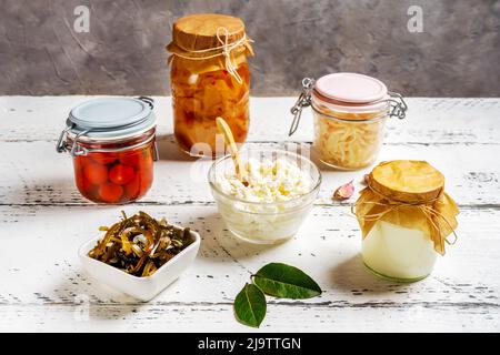 Eingelegte oder fermentierte Tomaten, Kimchi, Kohl, Algen, Joghurt, Quark auf weißem Holztisch mit grauem Hintergrund Stockfoto