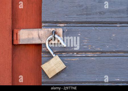 Altes, entriegeltes Vorhängeschloss an einer Holztür Stockfoto