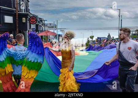 Das riesige farbenfrohe Banner, das von den Teilnehmern der Cornwall Prides Pride Parade im Zentrum von Newquay in Großbritannien getragen wurde. Stockfoto