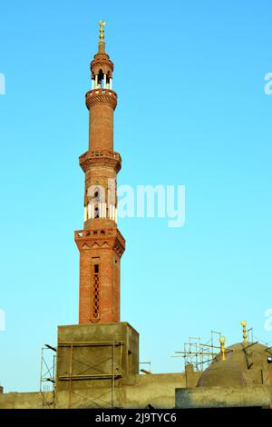 Ein hohes Minarett mit goldenem Ornament einer Moschee, die im Bau ist, Minarett oder Turm, der nach Himmel, islamischer Religion und Architektur strebt Stockfoto