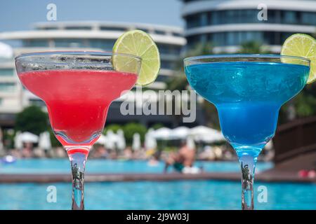Cocktails am Pool. Roter und blauer Cocktail auf einem Holztisch, im Urlaub. Sommer Stockfoto