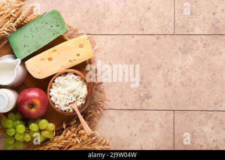 Glücklich Shavuot. Hintergrund für die Shavuot-Feier. Milch und Käse, reifer Weizen und Früchte, blauer Holzhintergrund. Milchprodukte über alten rissig til Stockfoto