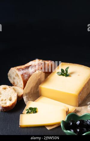 Food Concept Bio French Comté Käse mit französischem Brot Baquette auf schwarzem Schiefersteinbrett mit Kopierfläche Stockfoto