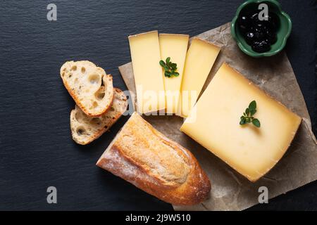 Food Concept Bio French Comté Käse mit französischem Brot Baquette auf schwarzem Schiefersteinbrett mit Kopierfläche Stockfoto