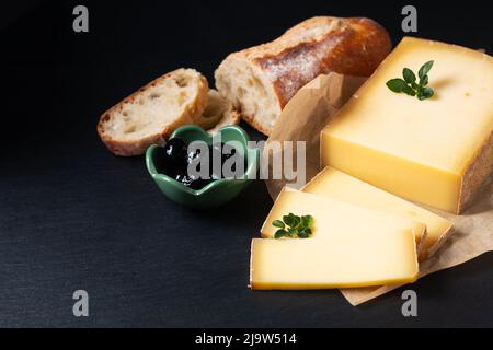 Food Concept Bio French Comté Käse mit französischem Brot Baquette auf schwarzem Schiefersteinbrett mit Kopierfläche Stockfoto