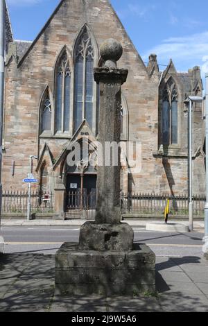 Ayr, Ayrshire, Schottland, Großbritannien. Das Mercat-Kreuz von Newton auf Ayr. Das Newton Market Cross steht jetzt in der Nähe der New Bridge. Der ursprüngliche Standort befand sich in der Mitte der Hauptstraße, gegenüber der Cross Street, heute King Street. Es wurde von dort ein paar Jahre vor 1847 verlegt. Das Kreuz hat einen einfachen quadratischen Schaft mit einer Basis. Rund um die Hauptstadt stehen die Worte 'Newton Cross - 1778'. Im Hintergrund ist der wettergetragene 2,0m hohe abgeschrägte Schaft und der 0,7m quadratische Sockel auf einem modernen Sockel zu sehen, der von einem quadratischen Sockel mit Kugelfinial überragt wird. Die Inschrift ist kaum lesbar. Stockfoto