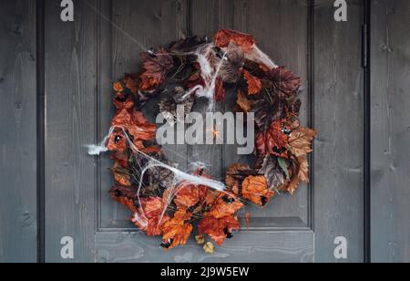 Bunte Kranz für halloween hängen an hölzernen Haus Tür aus alten orange Ahornblätter.Spider Web.Decorating von porch.Home, outdoort, Straße decora Stockfoto