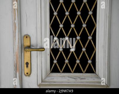 Altes klassizistisches Haus mit antikem weißen Holzeingang mit handgefertigten Zinngittern und einem Messinggriff. Stockfoto