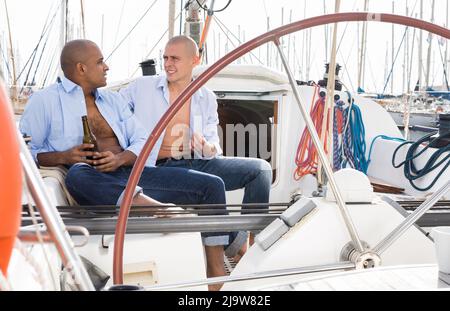 Ein paar Jungs in blauen Hemden plaudern auf einer privaten Segelyacht im Seehafen Stockfoto