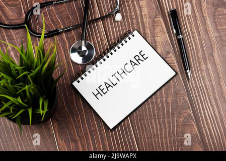 Gesundheitstext auf Notizblock mit Stethoskop, Stift und grüner Topfpflanze - Gesundheits- und Medizinkonzept Stockfoto