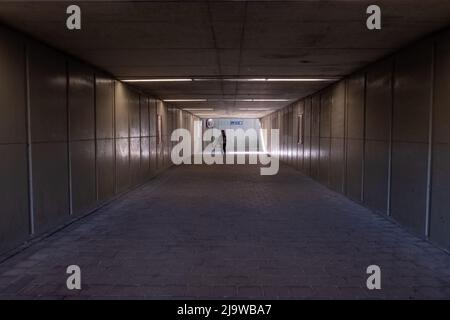 Die Frau geht den Tunnel hinunter zum Licht. Silhouette einer Frau, die in der Unterführung geht. Hochwertige Fotos Stockfoto