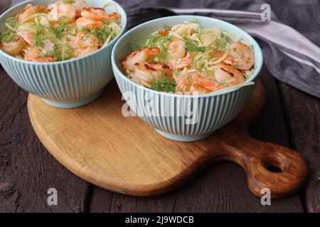 Zwei Schüsseln köstlicher Garnelen alfredo mit Knoblauch und Sahnesauce über Pasta auf rustikalem Holztisch Stockfoto
