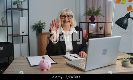 Eine Geschäftsfrau winkt mit der Handfläche in einer Geste und begrüßt ein Webinar im Heimbüro Stockfoto