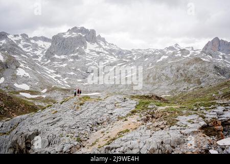 Umgeben von eisigen Berggipfeln erkunden einige Mitglieder einer Schultourgruppe am 18.. Mai 2022 in Asturien, Spanien, die felsige Landschaft in der Nähe der Seilbahnstation in Fuente De im spanischen Nationalpark Picos de Europa. Stockfoto