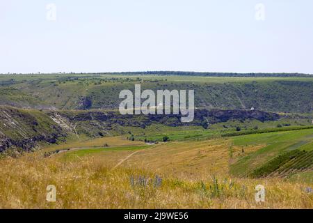 Schöne natürliche Schlucht mit Hügeln und einem Kloster auf der Oberseite, Gras, Felder und Bäume übersät. Am Ende der Schlucht fließt ein Fluss. Atemberaubende Landschaft für zu Stockfoto