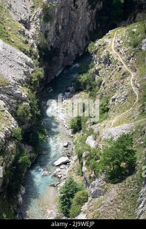 Am 15.. Mai 2022, in der Nähe von Poncebo, Picos Mountains, Asturien, Spanien, führt der Wanderer über den felsigen Weg in der Cares-Schlucht (Rio Cares), einem großen spanischen Wanderziel für Besucher des Nationalparks Picos de Europa. Der als „Göttliche Schlucht“ bekannte Wanderweg 22km erstreckt sich zwischen Caín und Poncebos in Asturien zwischen über 2.000 Meter hohen Bergen entlang der imposanten Schlucht, die vom Fluss Cares geformt wurde. Stockfoto