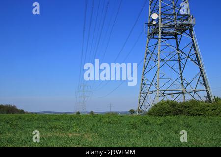 Mehrere Hochspannungsmasten gegen einen blauen Himmel Stockfoto