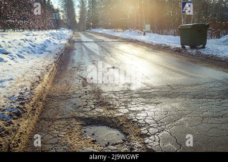 Große Grube an der alten Landstraße im Winter. Schlamm und Schnee. Im Freien Stockfoto