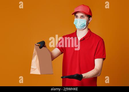Angestellter in roter Kappe Gesichtsmaske, leerer Pappkarton Stockfoto