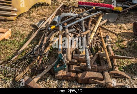 Ein Haufen von gebrauchten Outdoor-Werkzeugen für die Sanierung von Gebäuden und andere Wartungsarbeiten in einem Haufen auf den Boden an einem sonnigen Tag geworfen Stockfoto