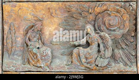 MONOPOLI, ITALIEN - 6. MÄRZ 2022: Das bronzene Relief Verkündigung am Tor der Kirche Chiesa di Sacro Cuore von Wolfgang Stempfele aus dem Jahr 2002. Stockfoto