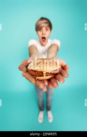 Sehr hungriger junger Mann mit leckeren Hamburgern Stockfoto