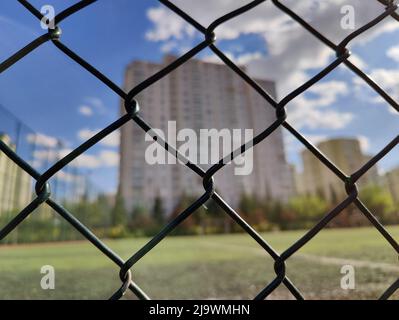 Hohes Gebäude hinter dem Zaun des Fußballfeldes Stockfoto