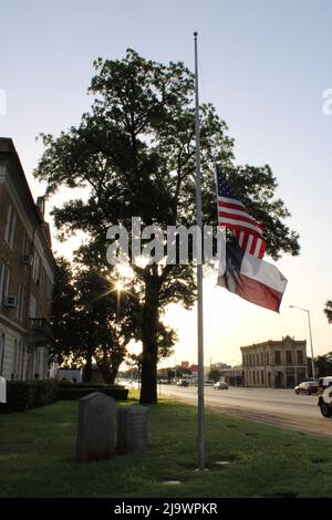 Uvalde, USA. 25.. Mai 2022. Flaggen fliegen am 25. Mai im Gerichtsgebäude von Uvalde County beim Sonnenaufgang in Uvalde, Texas, USA, auf Halb-Staff, 2022. Am 24. Mai 2022 fand in der Grundschule Robb in Uvalde eine Massenschießung statt, bei der 19 Kinder und 2 Erwachsene das Leben forderten. (Foto: Carlos Kosienski/Sipa USA) Quelle: SIPA USA/Alamy Live News Stockfoto