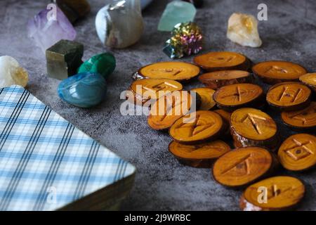 Handgemachte Holzrunen, verschiedene Mineralien und Tarot-Karten auf einem Steintisch Stockfoto