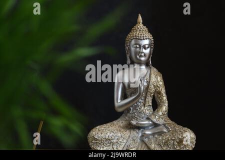 Buddha-Statue in Silber und Gold auf dunklem Hintergrund Stockfoto