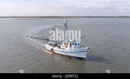 Niedrige Luftaufnahme eines Garnelenbootes, das Netze vor der Küste von South Carolina, USA zieht. Stockfoto