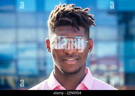 Portrait stilvoller und hübscher afrikanischer Student amerikanischer Mann mit coolen Dreadlocks und Ohrringin im Ohr Diamant-Mode-Look, der auf der Straße läuft Stockfoto