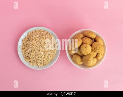 Flach Lay Haferflocken, Haferflocken Cookies auf einem weißen Teller auf einem rosa Hintergrund, Draufsicht, das Konzept der gesunden Ernährung und Herstellung von Müsli oder Cookies. Hochwertige Fotos Stockfoto