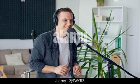 Ein Mann singt ein Lied mit einem Lächeln auf seinem Gesicht. Home Entertainer, Blogger-Konzept. Stockfoto