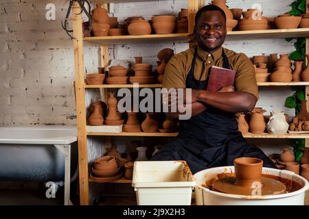 Junger und glücklicher Latino amerikanischer Geschäftsmann Formen eine handgemachte Ton Hände Topf Vase in Werkstatt. Bildhauer kreative Studio Arbeitsplatz Steingut Stockfoto