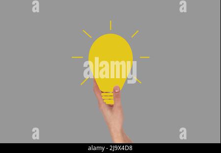 Hand hält die Glühbirne. Idee, Inspiration, Kreativität Konzept auf grauem Hintergrund. Hochwertige Fotos Stockfoto