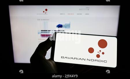 Person, die Mobiltelefon mit Logo des Biotechnologie-Unternehmens Bavarian Nordic AUF dem Bildschirm vor der Business-Webseite hält. Konzentrieren Sie sich auf die Telefonanzeige. Stockfoto