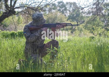 Ukrainische Soldatinnen, die mit einem Sturmgewehr bewaffnet sind, patrouilliert eine Kampfzone Stockfoto