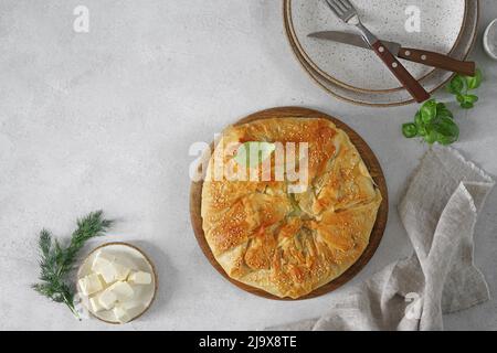 Köstliche goldene Kruste heißen griechischen Spinat Feta Käse Pie oder Spanakopita in Scheiben geschnitten auf weißem Tisch, authentisches Rezept, Draufsicht, Copy Space Stockfoto