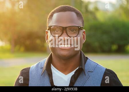 Porträt von jungen und schönen stilvollen Modell afro- amerikanischen Mann in einem stilvollen blauen Anzug Armbanduhr setzt auf eine Brille, in einem Sommerpark clever Latino Stockfoto